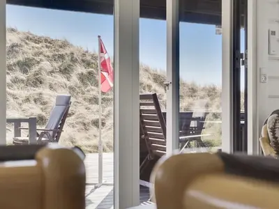 a room with a balcony with chairs and a flag at Holiday Home Baltur - 650m from the sea by Interhome in Saltum