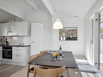 a white kitchen with a black table and chairs at Holiday Home Baltur - 650m from the sea by Interhome in Saltum