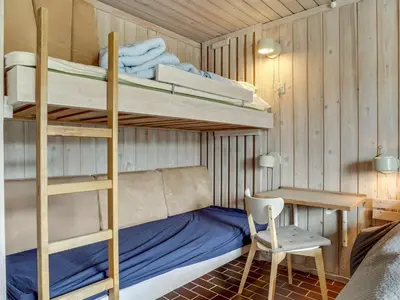 a bedroom with bunk beds with a desk and a chair at Holiday Home Emiljan - 400m from the sea by Interhome in Pandrup