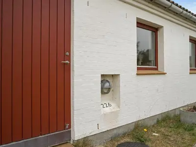 a house with a red door and a window at Holiday Home Emiljan - 400m from the sea by Interhome in Pandrup