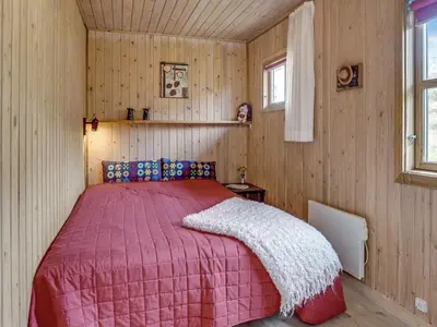 a bedroom with a bed with a red comforter at Holiday Home Marite - 200m from the sea by Interhome in Pandrup