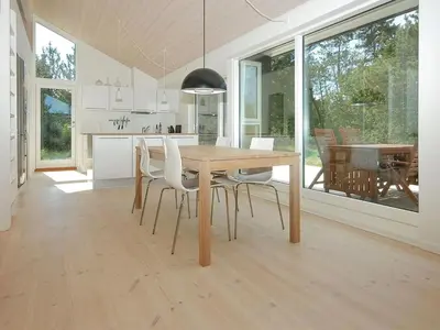 a kitchen and dining room with a wooden table and chairs at Holiday Home Melinda - 2km from the sea by Interhome in Pandrup