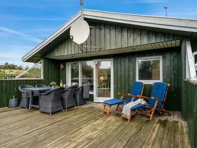 a green house with chairs and a table on a deck at Holiday Home Birghir - 1-5km from the sea by Interhome in Blokhus
