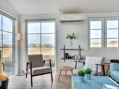 a living room with windows and a couch and a table at Holiday Home Zaharinka - 300m from the sea by Interhome in Pandrup