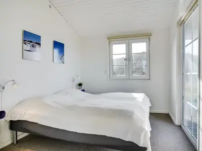 a white bedroom with a large bed and windows at Holiday Home Zaharinka - 300m from the sea by Interhome in Pandrup