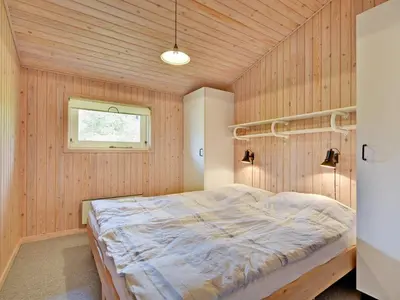 a bedroom with a bed in a wooden wall at Holiday Home Editt - 2km from the sea by Interhome in Pandrup