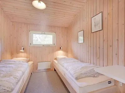 two beds in a room with wood paneled walls at Holiday Home Editt - 2km from the sea by Interhome in Pandrup