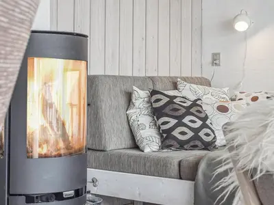a living room with a couch with a fireplace at Holiday Home Viena - 400m from the sea by Interhome in Pandrup