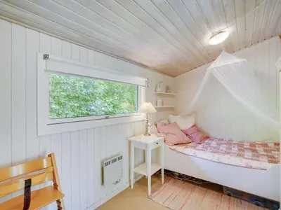 a small bedroom with a bed with a window at Holiday Home Angantir - 700m to the fjord by Interhome in Løgstør