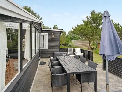 a patio with a wooden table and chairs and an umbrella at Holiday Home Githa - 100m to the fjord by Interhome in Løgstør