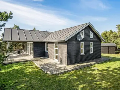 a black house with a deck in a yard at Holiday Home Anethe - 100m to the fjord by Interhome in Løgstør