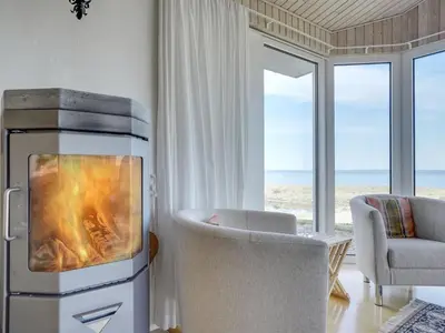a living room with a fireplace with a couch and a chair at Holiday Home Yorrick - 50m to the fjord by Interhome in Løgstør