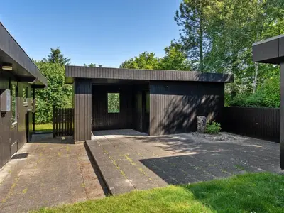 a house with a wooden garage with a driveway at Holiday Home Ludde - 500m to the fjord by Interhome in Løgstør