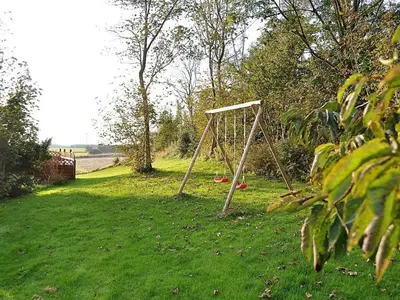 a swing set in the middle of a grass field at Holiday Home Millie - 3km to the fjord by Interhome in Løgstør