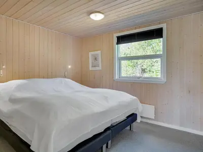 a bedroom with a large white bed with a window at Holiday Home Wilja - 400m from the sea by Interhome in Fjerritslev