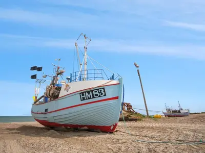 a boat sitting on the sand on a beach at Holiday Home Wilja - 400m from the sea by Interhome in Fjerritslev