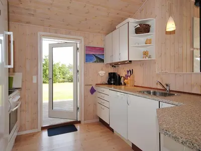 a kitchen with white cabinets and a sliding glass door at Holiday Home Einette - 3-5km from the sea by Interhome in Fjerritslev