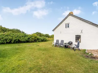a white building with chairs in a field at Holiday Home Agrippa - 30m to the fjord by Interhome in Løgstør
