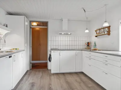 a white kitchen with white cabinets and a wooden floor at Holiday Home Justine - 600m from the sea by Interhome in Fjerritslev