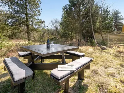 a picnic table with a bottle of wine and two benches at Holiday Home Sighbiorn - 950m from the sea by Interhome in Fjerritslev