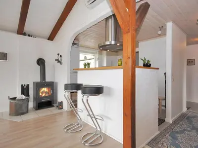 a living room with a fireplace and two stools at Holiday Home Oberon - 3km from the sea by Interhome in Fjerritslev