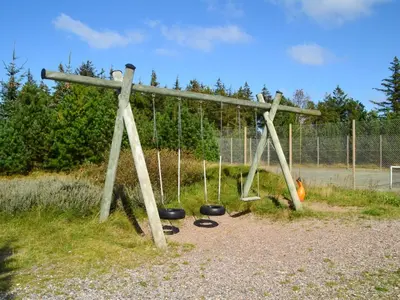 a swing set in a park with three swings at Holiday Home Roulf - 1-1km from the sea by Interhome in Fjerritslev