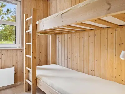 a bunk bed in a cabin with wooden walls and a window at Holiday Home Karitte - 5km from the sea by Interhome in Fjerritslev