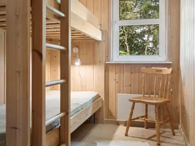 a bedroom with bunk beds and a chair and a window at Holiday Home Karitte - 5km from the sea by Interhome in Fjerritslev