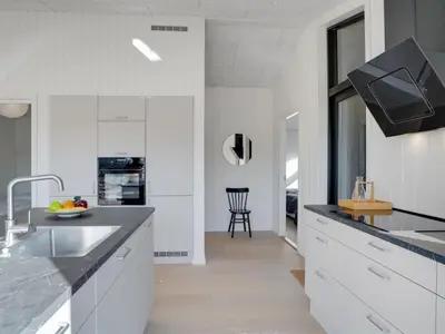 a kitchen with white cabinets and black counter tops at Holiday Home Vigga - 800m from the sea by Interhome in Fjerritslev