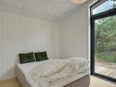 a bedroom with a bed with white sheets and a window at Holiday Home Vigga - 800m from the sea by Interhome in Fjerritslev