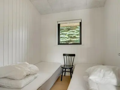 a bedroom with two beds and a chair and a window at Holiday Home Vigga - 800m from the sea by Interhome in Fjerritslev