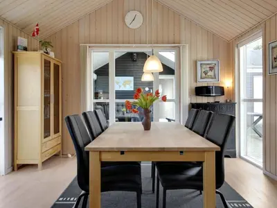 a dining room with a wooden table and black chairs at Holiday Home Henriete - 3-5km from the sea by Interhome in Fjerritslev