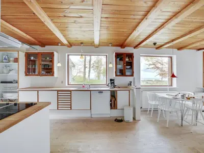 a kitchen with wooden ceilings and a table and chairs at Holiday Home Nella - 1-2km from the sea by Interhome in Fjerritslev