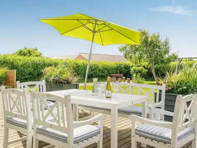 a white table and chairs with a yellow umbrella at Holiday Home Swipdagh - 600m from the sea by Interhome in Fjerritslev