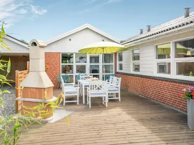 a patio with a table and chairs and an umbrella at Holiday Home Swipdagh - 600m from the sea by Interhome in Fjerritslev