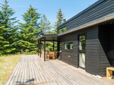 a wooden deck next to a black house at Holiday Home Gunnor - 1-3km from the sea by Interhome in Fjerritslev