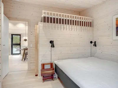 a bedroom with a bed and a wooden wall at Holiday Home Gunnor - 1-3km from the sea by Interhome in Fjerritslev