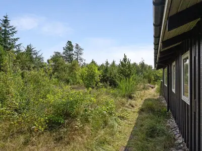 a side of a house with a field and trees at Holiday Home Asmo - 350m from the sea by Interhome in Fjerritslev