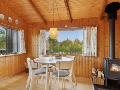 a dining room with a table and chairs and a stove at Holiday Home Asmo - 350m from the sea by Interhome in Fjerritslev