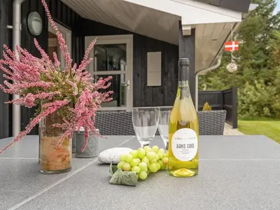 a bottle of wine and a bunch of grapes on a table at Holiday Home Frida - 700m from the sea by Interhome in Fjerritslev