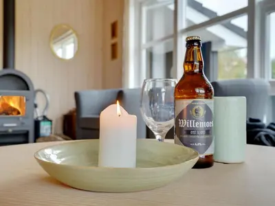 a bottle of beer and a candle on a table at Holiday Home Frida - 700m from the sea by Interhome in Fjerritslev