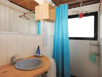 a bathroom with a sink and a blue shower curtain at Holiday Home Deni - 4km from the sea by Interhome in Fjerritslev