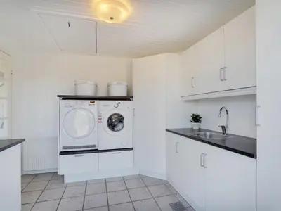 a white kitchen with a washer and dryer at Holiday Home Bitta - 500m from the sea by Interhome in Fjerritslev