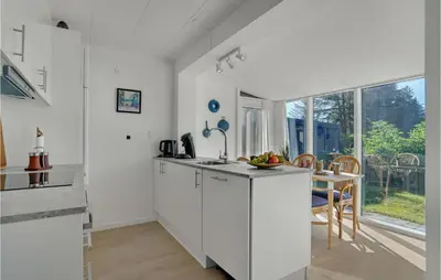 a kitchen with white cabinets and a table and chairs at 2 Bedroom Gorgeous Apartment In Blokhus in Blokhus