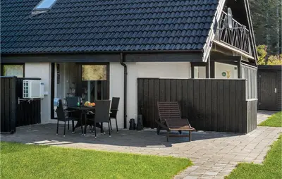 a patio with a table and chairs in front of a house at 2 Bedroom Gorgeous Apartment In Blokhus in Blokhus