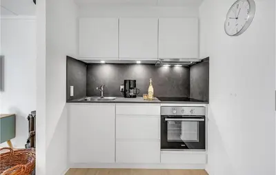 a kitchen with white cabinets and a clock on the wall at Cozy Home In Lemvig With Wifi in Lemvig