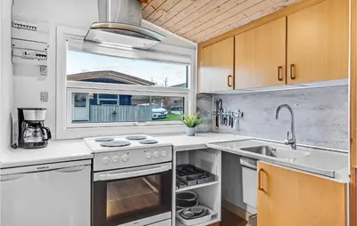 a kitchen with a stove and a sink and a window at Lovely Home In Hanstholm With Kitchen in Hanstholm