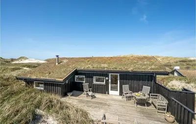 a black house with a grass roof on a wooden deck at Beautiful Home In Pandrup With Wifi in Pandrup