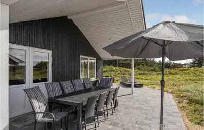 a table with chairs and an umbrella on a patio at Cozy Home In Vestervig With Wifi in Vestervig