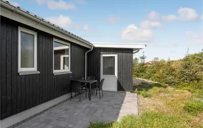 a black house with a table and chairs on a patio at Cozy Home In Vestervig With Wifi in Vestervig